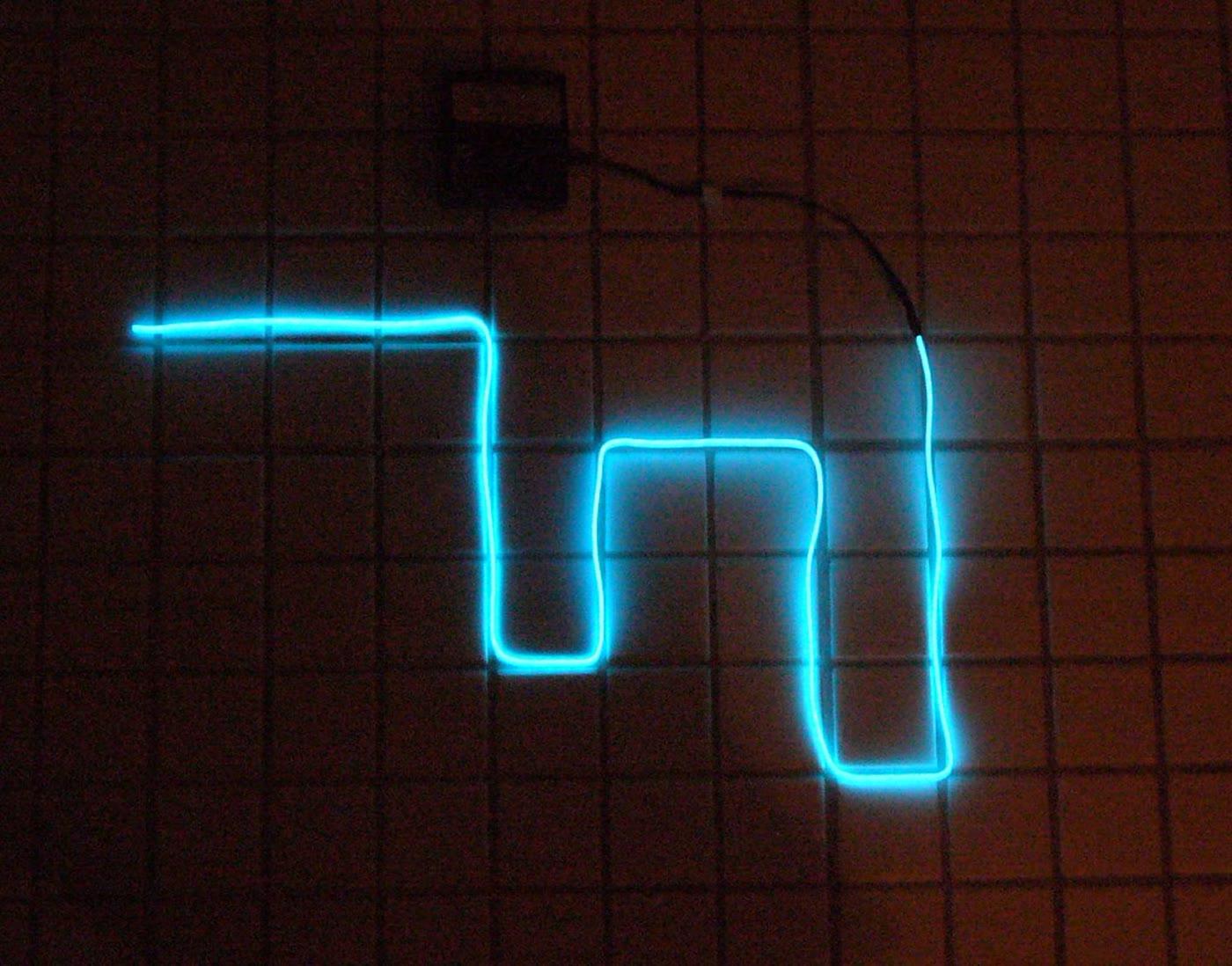 A coil of electroluminescent wire glowing on a workbench.