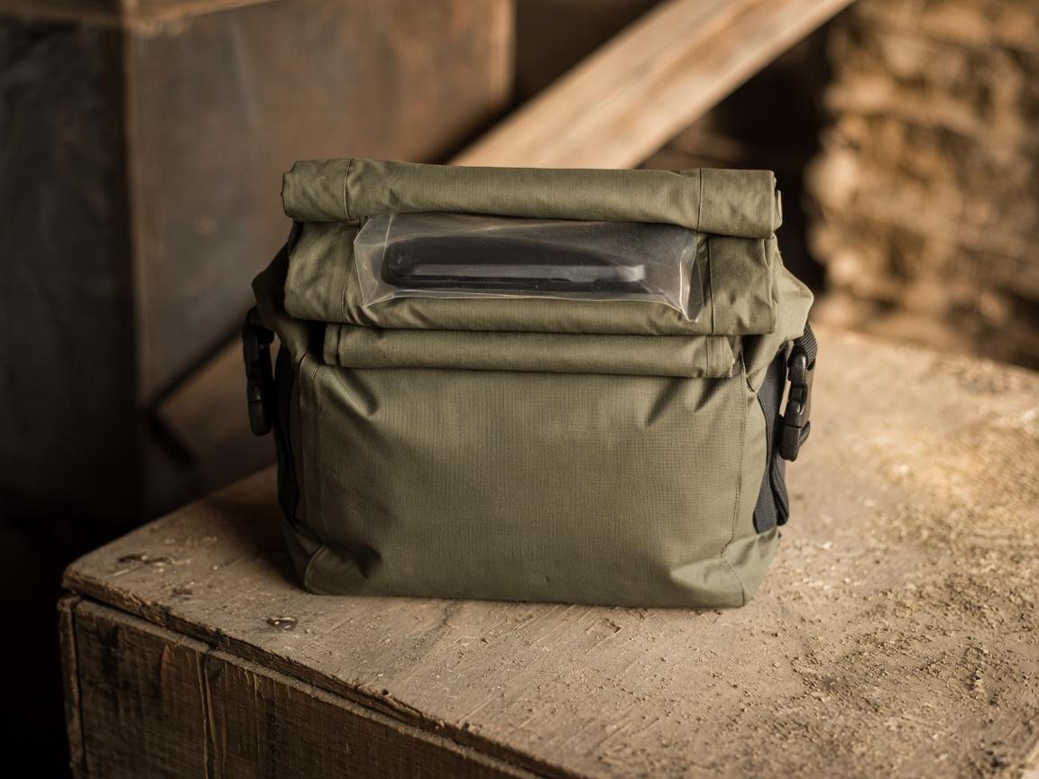 A small roll-top dry bag closed on a dusty crate.